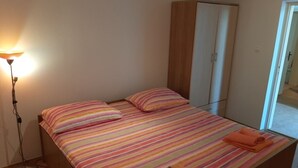 Un lit simple avec une literie à rayures, une armoire et une lampe de chevet.