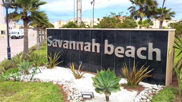 A sign for 'Savannah Beach' with a landscaped garden featuring various plants and a small tree. - Very nice apartment in Savannah Beach 4210 (Sidi Rahal)
