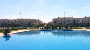 A swimming pool surrounded by buildings with a clear sky. - Very nice apartment in Savannah Beach 4210 (Sidi Rahal)