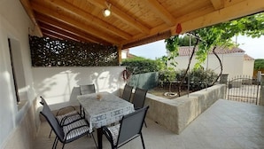 An outdoor patio with a table and chairs, a wooden ceiling, and a view of a garden and building in the background. - Holiday Home in Miholaščica with Terrace, Air condition, WIFI (66-1) (Miholašcica)