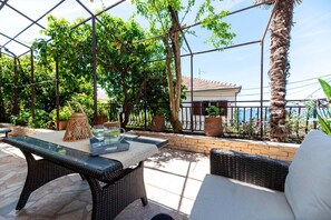 An outdoor patio with wicker furniture, a table with a glass top, and potted plants. - Apartment in Trogir with Seaview, Terrace, Air condition, WIFI (3459-3) (Trogir)