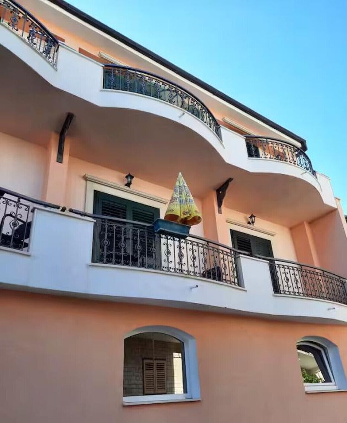 Un immeuble à plusieurs étages doté de balcons, de fenêtres et d’un parasol décoratif.