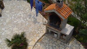 A stone patio with a stone oven and a potted plant.