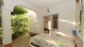 A sunlit patio with a table and chairs, surrounded by potted plants and an archway. - Apartment in Kustici with Seaview, Terrace, Air condition, WIFI (3597-5) (Kustici)