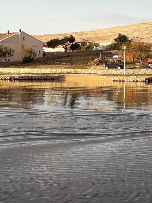 Une étendue d'eau calme dans laquelle se reflètent un bâtiment et une voiture.