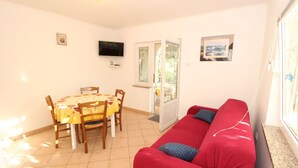 A room with a dining table, chairs, a red sofa, a TV, and a window with a view. - Apartment in Kustici with Seaview, Terrace, Air condition, WIFI (3597-5) (Kustici)