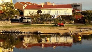 A residential area with a house featuring a red roof, a small garden, and a pond with floating buoys. - Apartment in Kustici with Seaview, Terrace, Air condition, WIFI (3597-5) (Kustici)