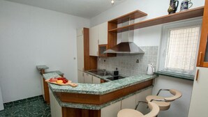 A compact kitchen with a granite countertop, a built-in stove, and a window with a decorative screen. - Apartment in Duće with Seaview, Balcony, Air condition, WIFI (4172-1) (Duce)