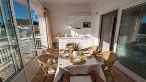 A balcony dining area with wicker chairs, a table set for four, and a kitchen in the background. - Apartment in Duće with Seaview, Balcony, Air condition, WIFI (4172-1) (Duce)