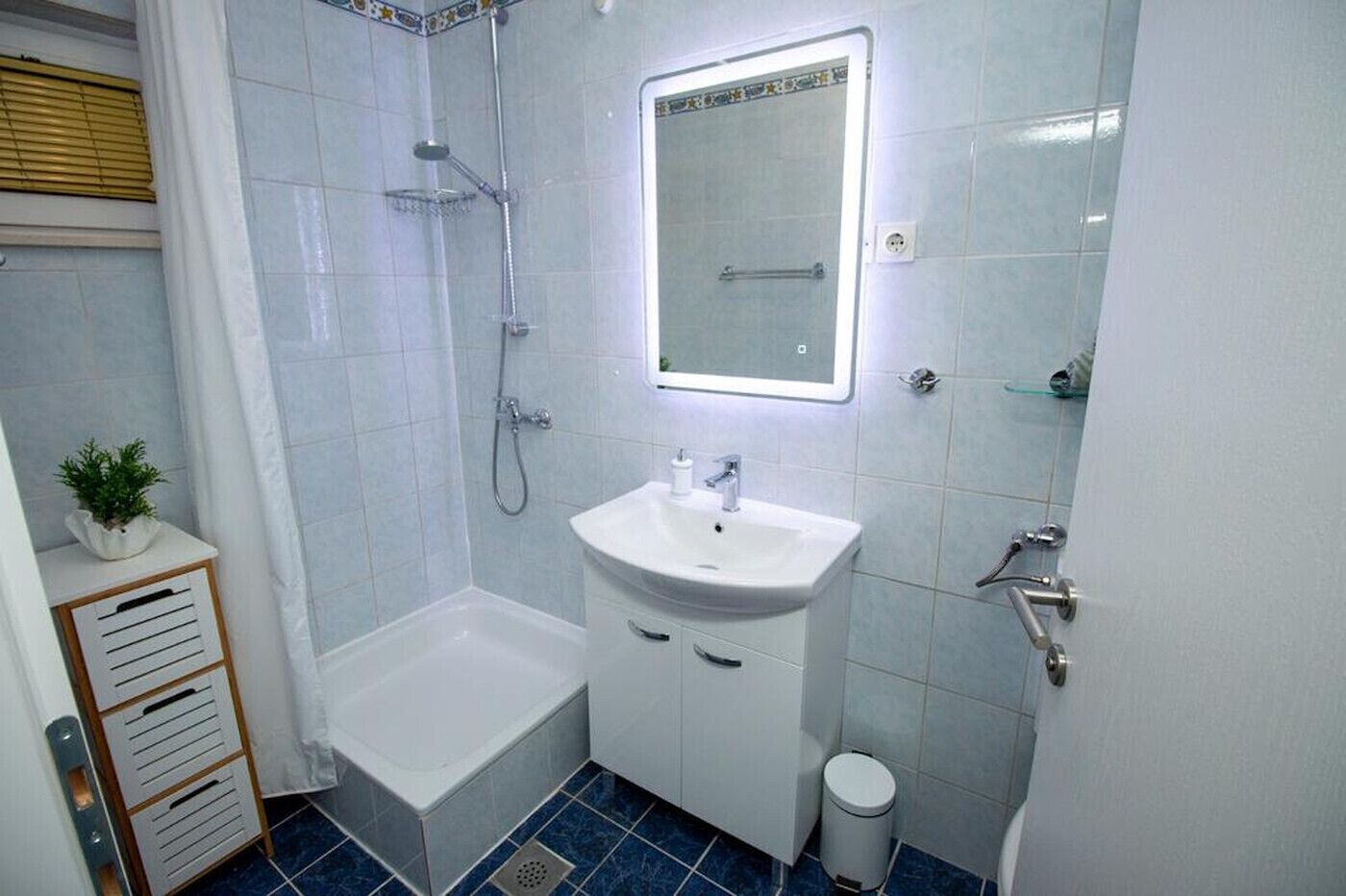 Ein Badezimmer mit Badewanne, Waschbecken, Dusche und einem kleinen Mülleimer.