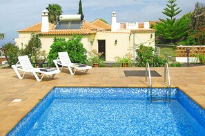 A swimming pool with lounge chairs, a tiled deck, and a house with a tiled roof in the background. - Casa Mar in Tijarafe (Tijarafe)
