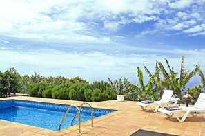 A swimming pool with lounge chairs and a view of the ocean.