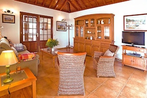 A living room with a sofa, armchairs, a coffee table, a TV, and a cabinet.
