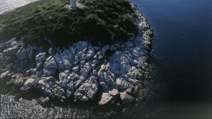 A lighthouse on a rocky island with a mountain in the background and calm water. - Apartment in Žuljana with Seaview, Terrace, WIFI, Dishwasher (3558-2) (Žuljana)