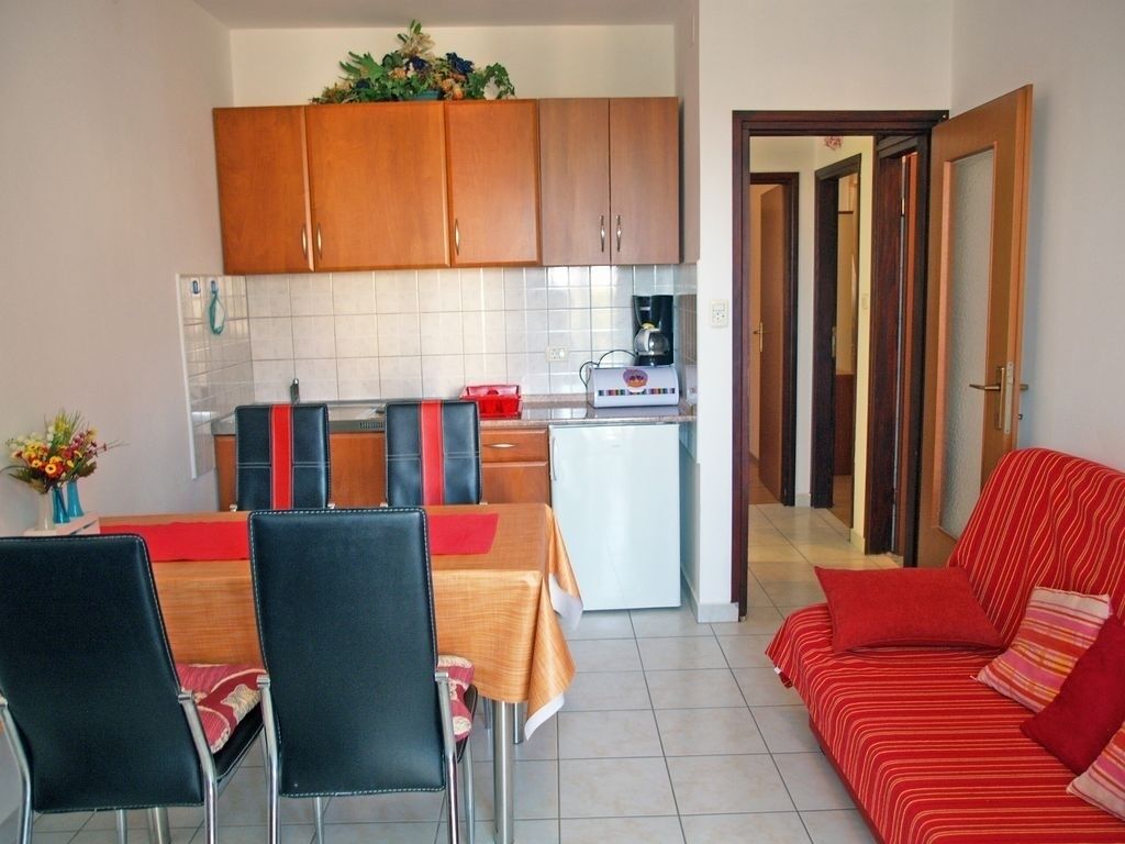 A compact living space with a kitchenette, a dining area with a table and chairs, and a red sofa.