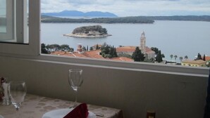 Ein Tisch mit einem Glas und einer roten Servieette, mit Blick auf einen See mit einer kleinen Insel und Gebäuden in der Ferne.