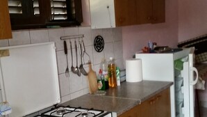 A kitchen with a gas stove, oven, wooden cabinets, a refrigerator, and various kitchen utensils. - Apartment in Basina with Seaview, Terrace (3450-3) (Stari Grad)