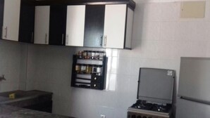 Una cocina con estufa a gas, refrigerador y alacenas sobre el fregadero.
