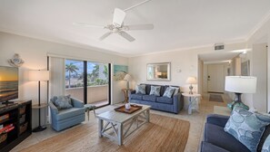 A living room with a ceiling fan, a blue sofa, a coffee table, and a TV.