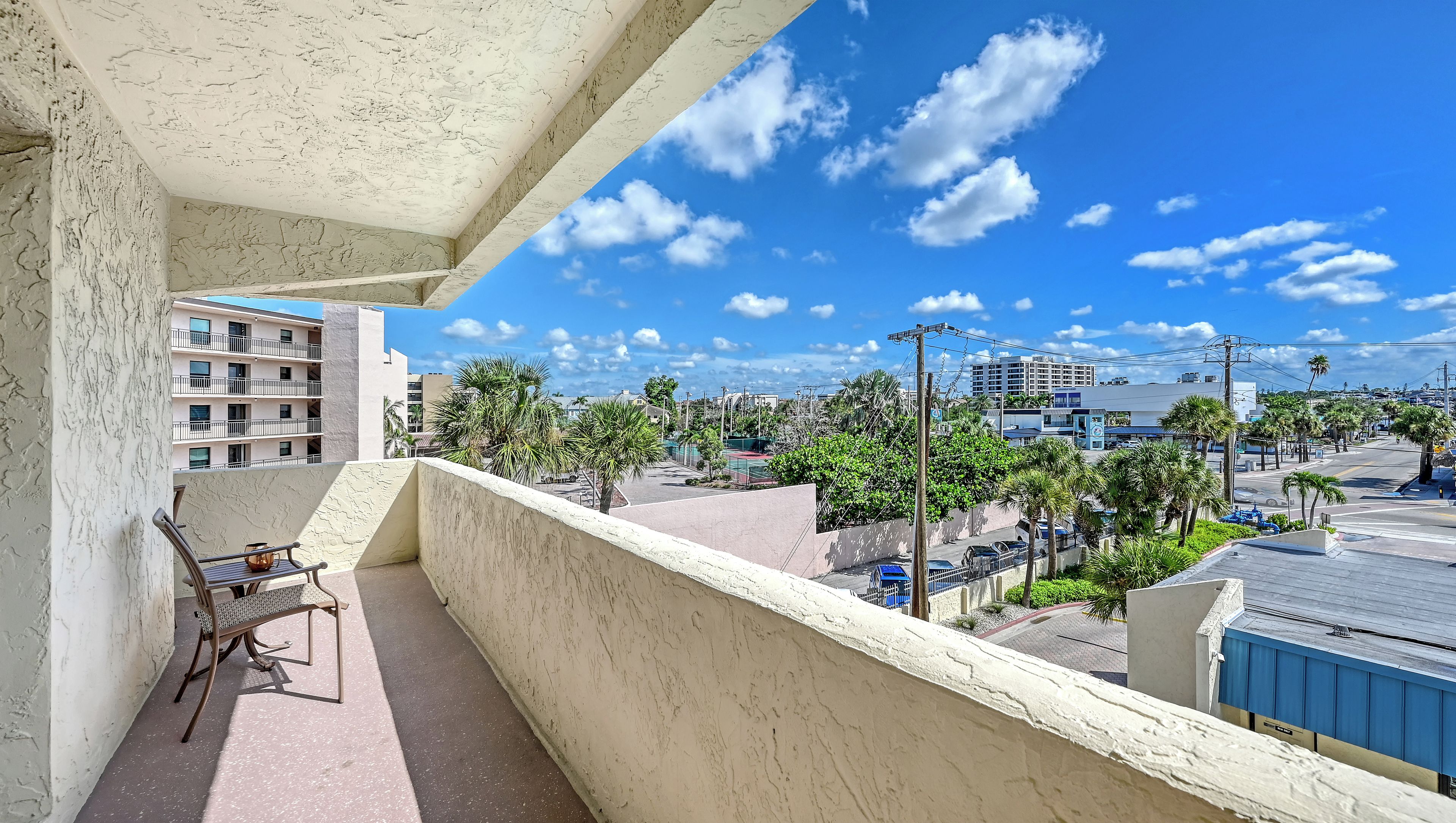 A balcony with a view of a cityscape, including buildings and palm trees.