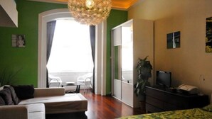 Ein Hotelzimmer mit Bett, einer Sitzecke, Schreibtisch, Fernseher und einer Pflanze.