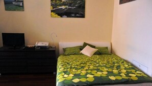 Ein Schlafzimmer mit einem Bett, einem Schminktisch, einem Fernseher und einem Telefon.