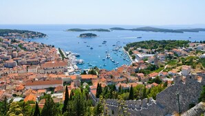 A coastal town with historic buildings, a marina, and a prominent stone wall.