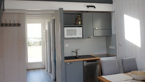 Una cucina compatta con forno a microonde, lavello e piccolo frigorifero. C'è un'area pranzo con tavolo e sedie.
