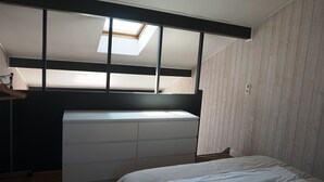 Una camera da letto con un lucernario, una cassettiera bianca e un letto.