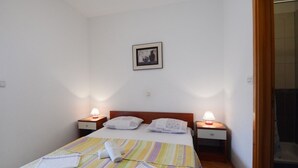 A neatly made bed with striped bedding, two bedside lamps, and a framed picture on the wall. - Apartment in Omiš with Seaview, Terrace, Air condition, WIFI (3422-3) (Omiš)