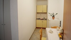 A compact kitchen with yellow cabinets, a sink, and a small table with chairs. - Apartment in Omiš with Seaview, Terrace, Air condition, WIFI (3422-3) (Omiš)