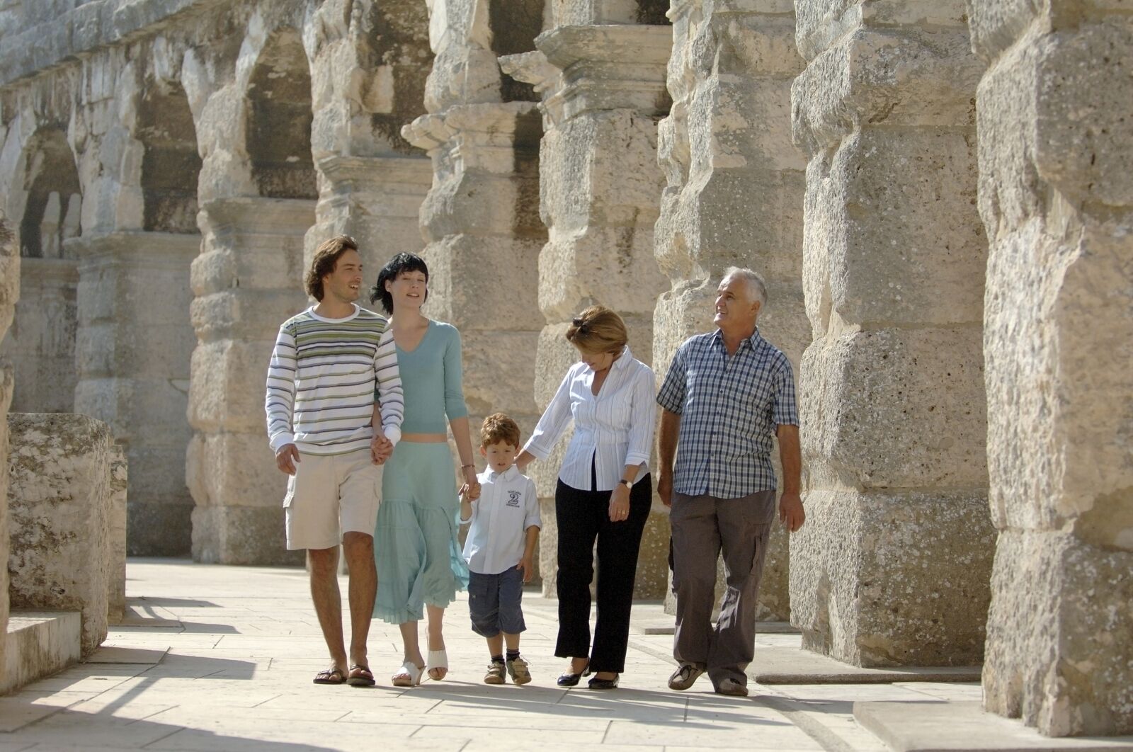 A family walking through an ancient stone structure with columns.