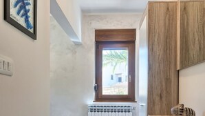 Ein schmaler Flur mit Heizkörper, Holzschrank und einem gerahmten Kunstwerk an der Wand.
