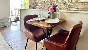 A dining table with two leather chairs, a vase with flowers, and a bottle of wine. - The Owlery at Aysgarth (Aysgarth, near Leyburn)
