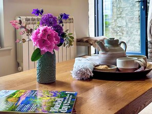 A wooden table with a vase of flowers, a teapot, cups, and a magazine. - The Owlery at Aysgarth (Aysgarth, near Leyburn)