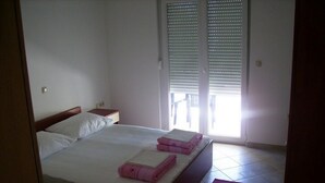 Una camera da letto con un letto, due comodini, una finestra con persiane e un tappeto rosso.