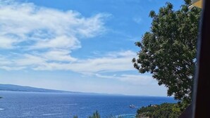 Un espace extérieur aménagé avec une table et des chaises, offrant une vue sur la côte et un ciel dégagé.