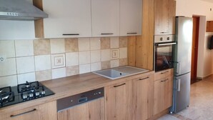 Una cocina moderna con armarios de madera, un refrigerador de acero inoxidable y un horno empotrado.