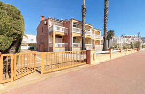 A multi-story building with balconies, a gated entrance, and palm trees. - 0015-BAHIA Apartment in front of the beach with wifi (Empuriabrava)