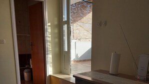 Une cuisine avec un carrelage à motifs, une fenêtre et un ordinateur posé sur le plan de travail.