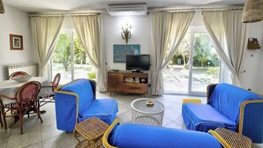 Una sala de estar con sofás azules, un televisor y un comedor con mesa y sillas.