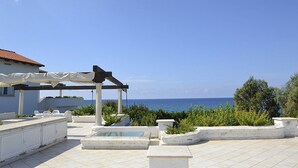 Una terraza en la azotea con piscina, mobiliario exterior y vistas al mar.