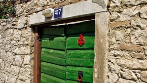 Un mur de pierre avec une porte verte sur laquelle est fixée une plaque d’immatriculation.