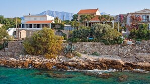 A coastal property with stone walls, a clear view of the sea, and buildings with Mediterranean architecture.