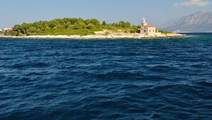 A coastal scene with a small island featuring a lighthouse and lush greenery.