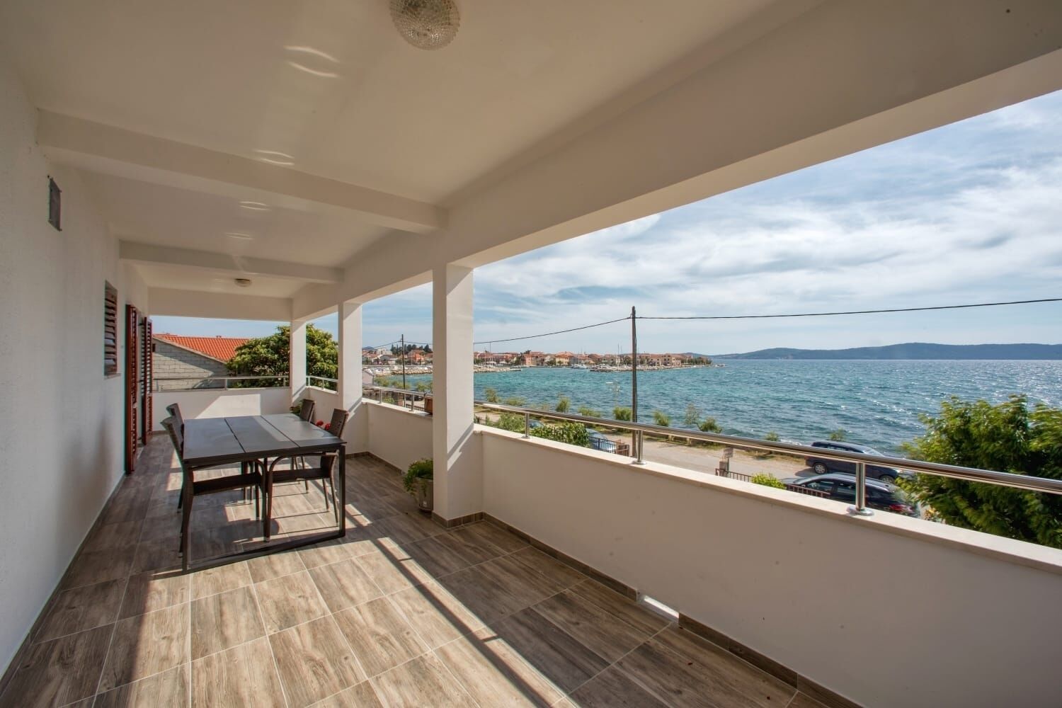 A balcony with a table and chairs, overlooking a body of water and a distant shoreline.