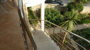 Un escalier avec des rampes en métal menant à un espace extérieur agrémenté de verdure.