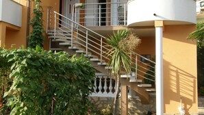 Un immeuble à plusieurs étages, doté d’un escalier blanc, d’un balcon et d’une citerne d’eau.