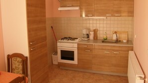 Une cuisine compacte avec des meubles de rangement en bois, une cuisinière à gaz, une machine à café et un évier.
