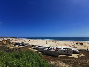 A beach with several white mobile homes labeled "CASTELO" and a sandy path leading to the sea.